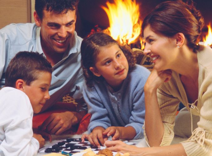 La famiglia intorno al camino a legna che si diverte con i giochi di famiglia